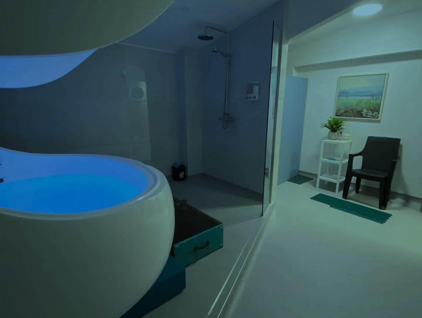 A white float pod with glowing turquoise water in a bright float room