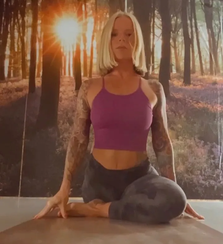 A teacher in pigeon pose in front of the bluebell mural