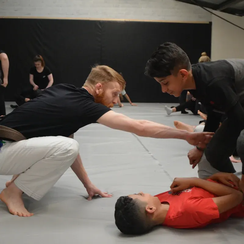 Paddy Holohan on the mats, leaning in to help a child